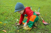 Kind, das auf einer Wiese mit Gartenwerkzeugen und Schubkarre spielt © Pixabay